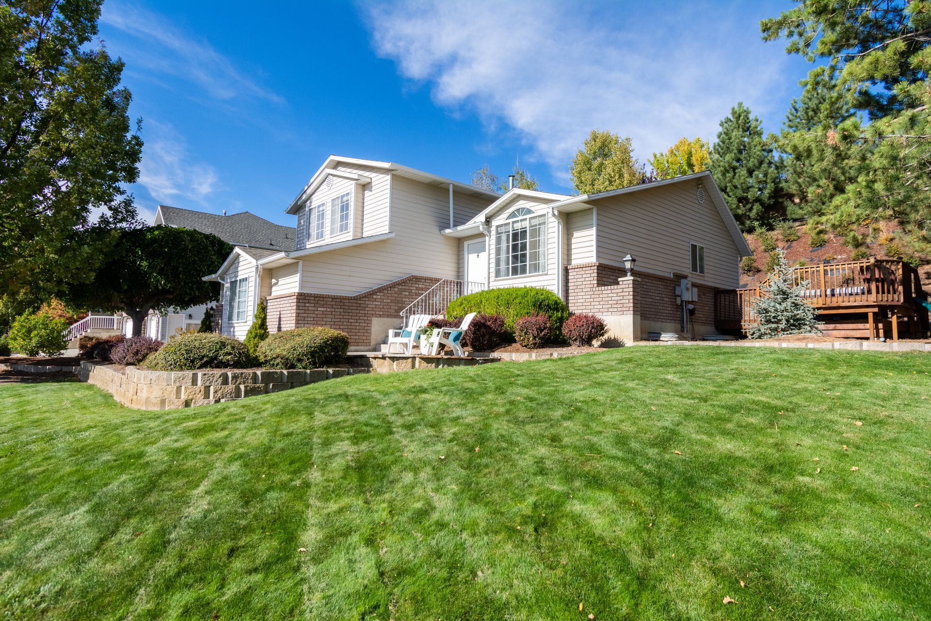 Well-kept suburban home with a deep green, freshly cut lawn under a clear sky