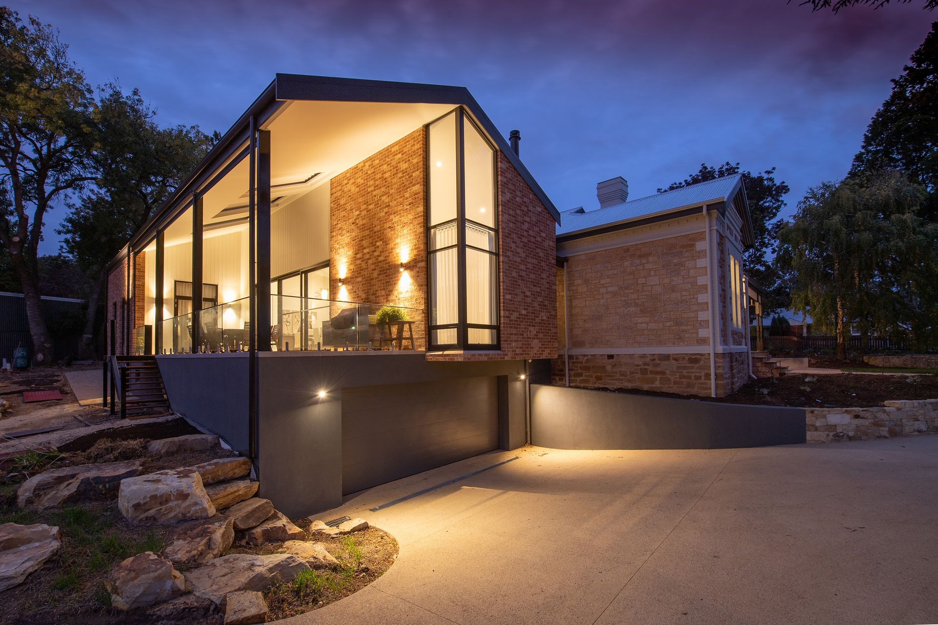 Modern home at dusk with warm architectural lighting washing the walls and walkway